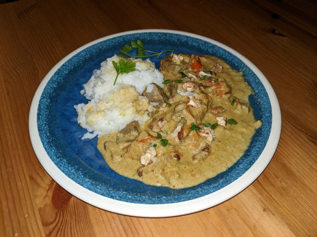 Beef korma with a parsley and walnut garnish, white rice on the side
