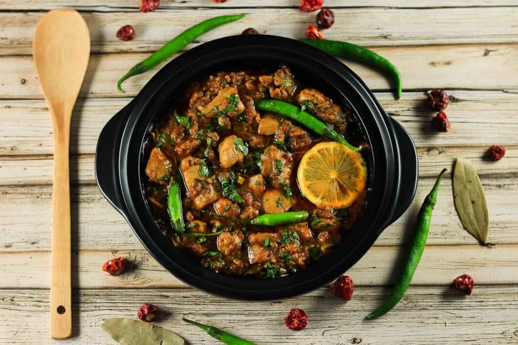 A chicken karahi curry with lemon, chicken , and green chilies