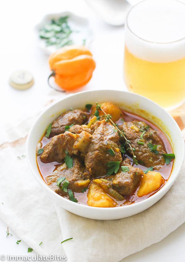 a red, soupy curry with large chunks of goat meat and potatoes