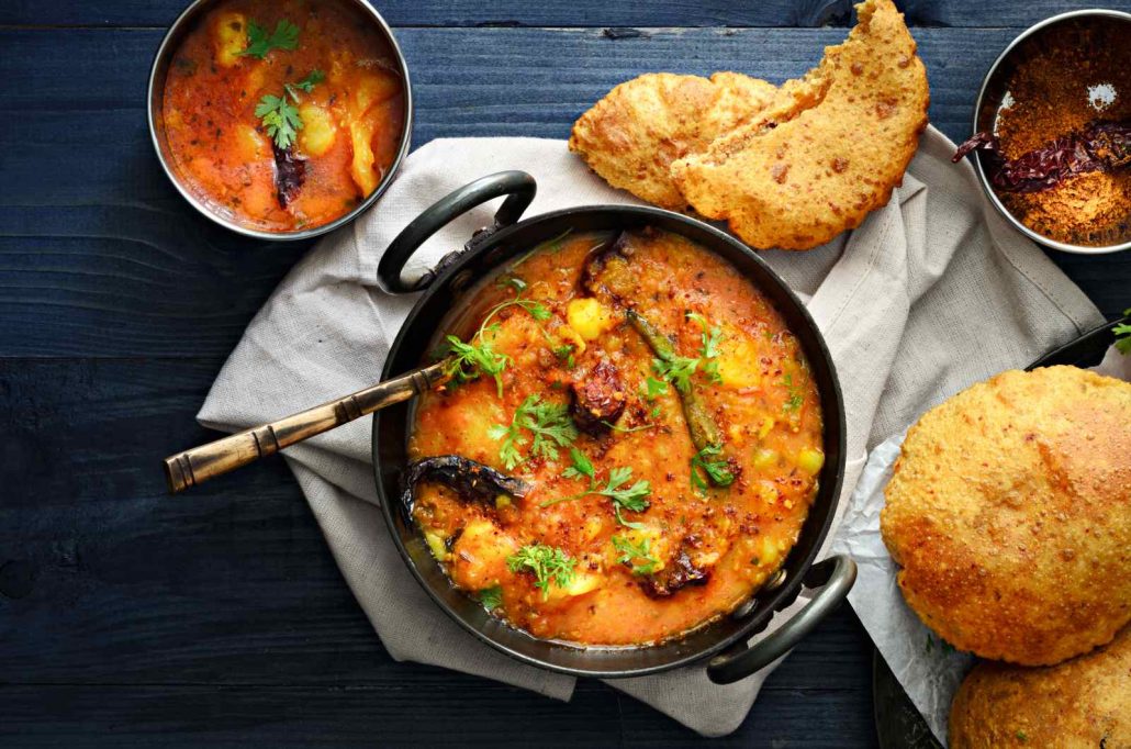An orange curry, with potatoes as the focus, surrounded by tasty bread
