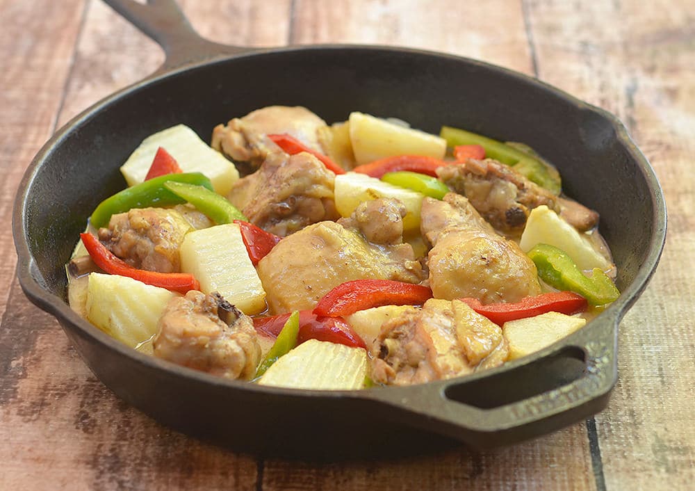 A sast iron skillet with chicken, onion, red and green bell pepper in a creamy curry sauce