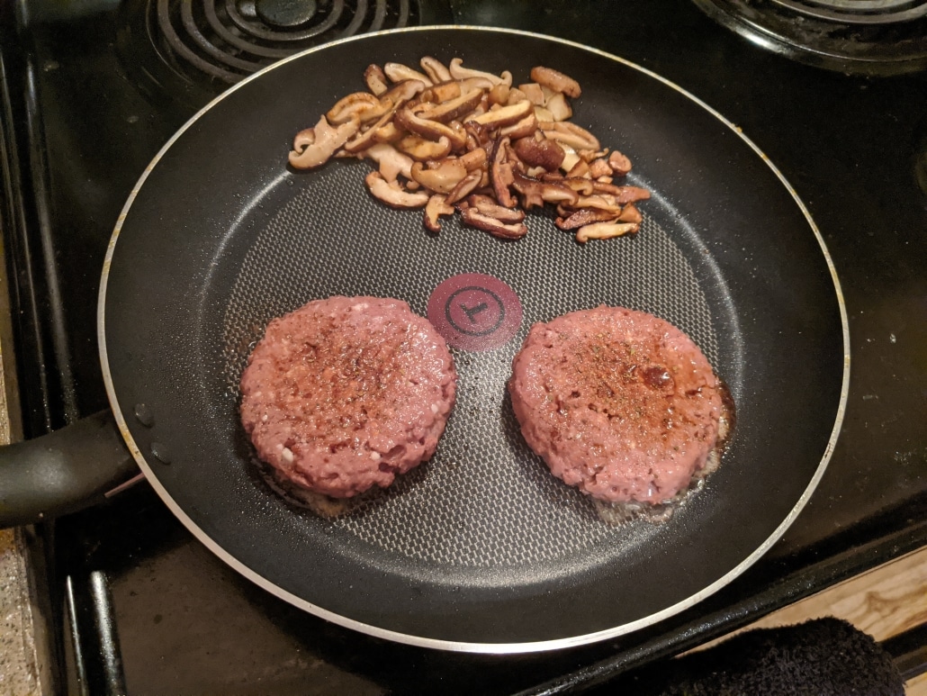 Cooking vegan burgers and mushrooms.
