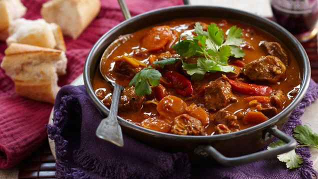 A dark brown roux like curry with carrots, beef, and coriander