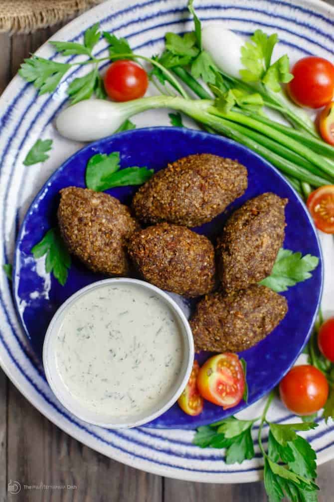 Crunchy oval shaped dumplings called kibbeh with a tzatziki sauce