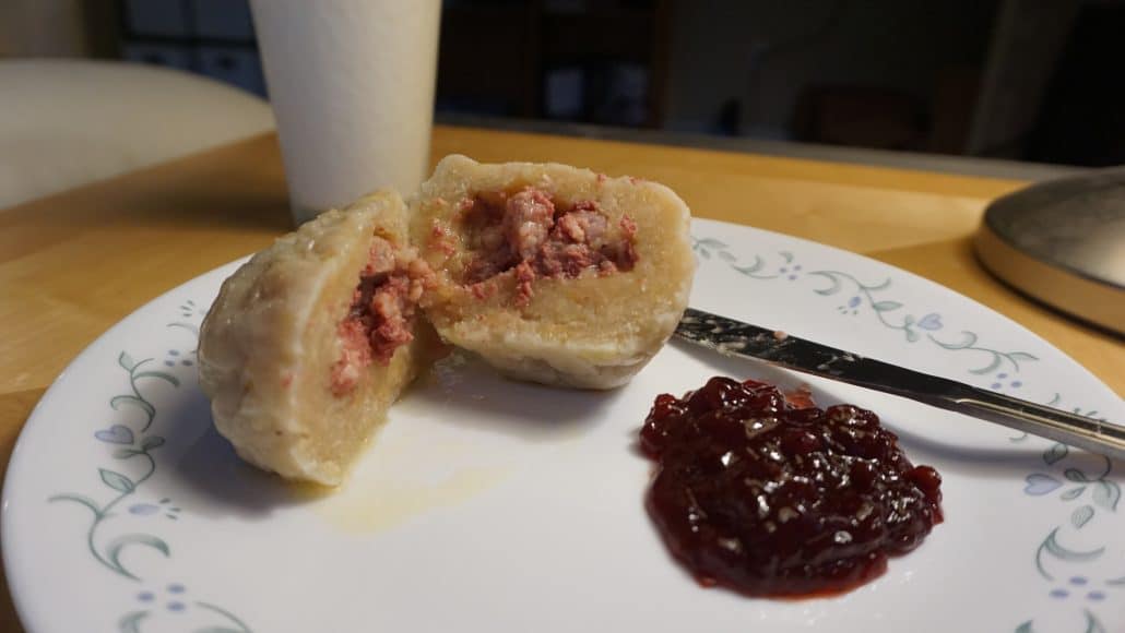 Palt cut in half, with pork in the middle, and beet jam on the side