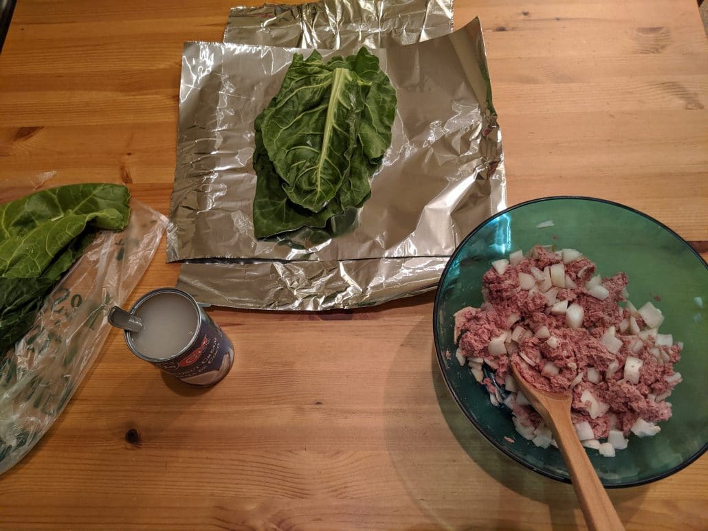 Mixing bowl of filling, can of coconut cream, and Swiss chard leaves ready for filling.