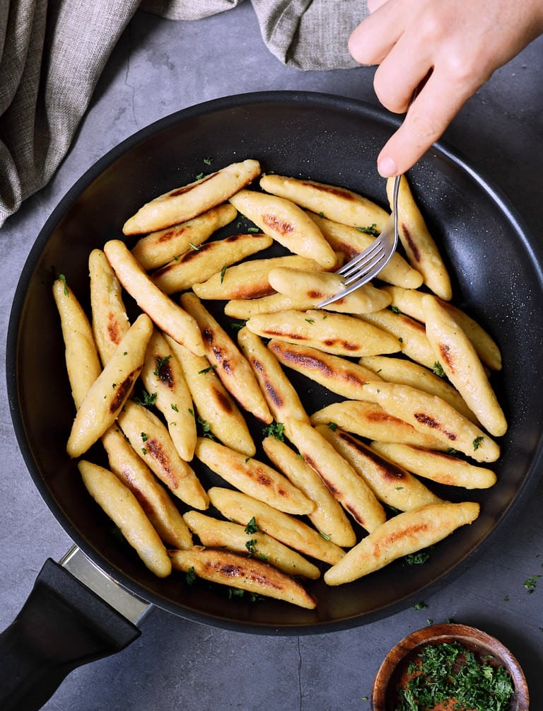 Skinny potato dumplings called schupfnudeln in a black skillet