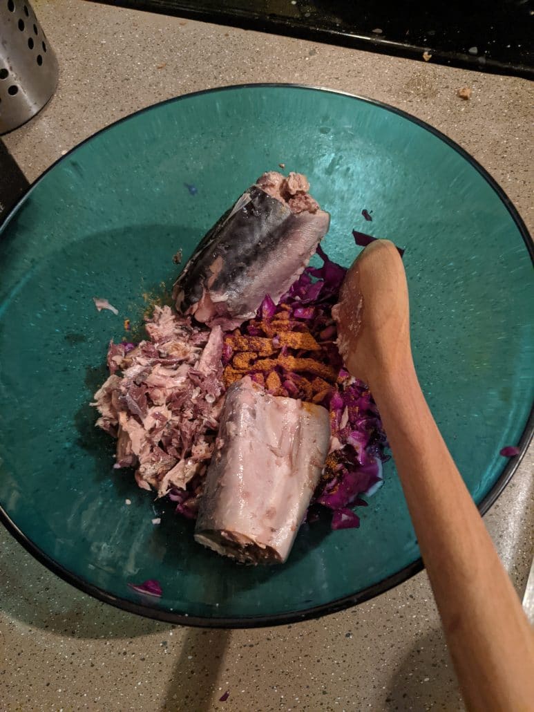 Canned mackerel being added to chopped cabbage