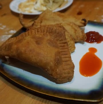 4 fataya on a plate with hot sauce and ketchup