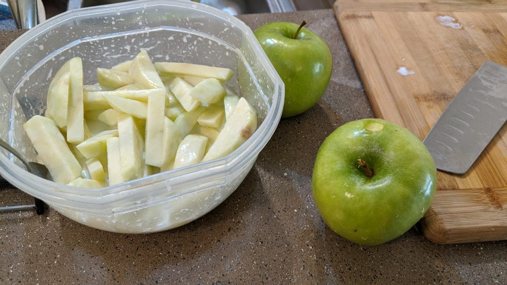 Granny Smith apple slices soaking in a bowl of buttermilk