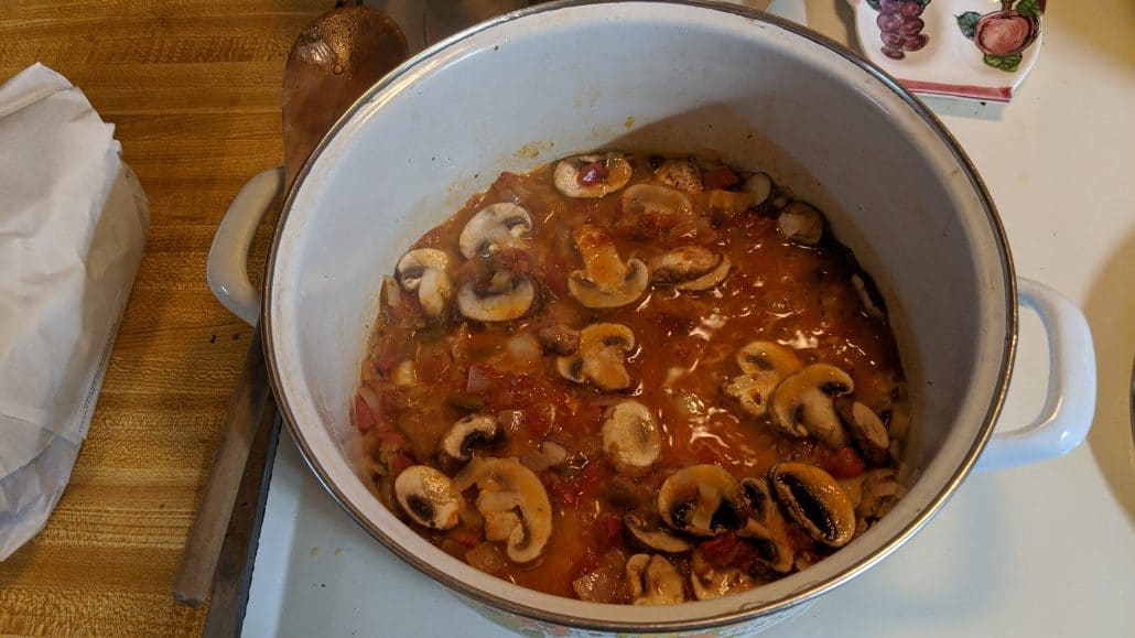 Shallots, diced tomato, and mushrooms in the seafood risotto pot